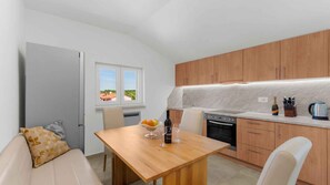 Une cuisine compacte avec des meubles en bois, un four encastré et un coin repas comprenant une table et des chaises.