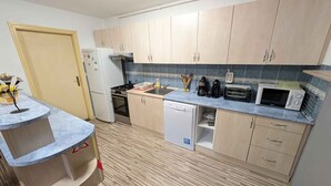 A compact kitchen with light wood cabinets, a white refrigerator, a stove, a microwave, and a dishwasher. - Holiday home with wifi and air conditioning (Ságvár)