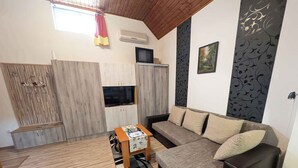 A modern living room with a sofa, a coffee table, a TV, and a wooden cabinet. - Holiday home with wifi and air conditioning (Ságvár)