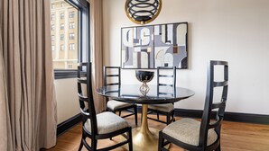 A dining area with a round table, four chairs, a decorative bowl, and a modern abstract painting on the wall. - 1BR Penthouse Steps to French Quarter | The Mayfair (New Orleans)