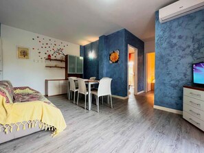 Une chambre moderne avec un lit, un coin repas avec des chaises et un téléviseur.