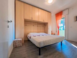 A bedroom with a bed, wooden wardrobe, and a small bench.