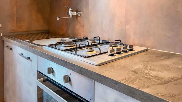 Eine moderne Küche mit Gasherd, Edelstahlgeräten und minimalistischem Design.