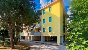 Ein modernes mehrgeschossiges Gebäude mit gelber Fassade, zahlreichen Fenstern und einem überdachten Außenbereich.