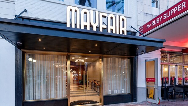 A Mayfair hotel entrance with a large glass facade, a visible staircase leading to the interior, and a sign for 'The Ruby Slipper' adjacent to the entrance. - 3BR Charming Stay Walk to French Quarter | The Mayfair (New Orleans)