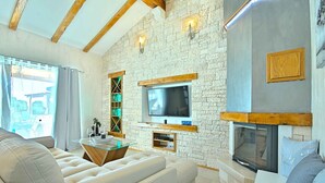A modern living room with a stone wall, a flat-screen TV, a fireplace, and a comfortable sofa. - Villa with air conditioning and pool (Nova Vas/Novigrad)