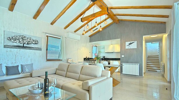 A modern living room with a sofa, glass coffee table, and a dining area with a chair. - Villa with air conditioning and pool (Nova Vas/Novigrad)