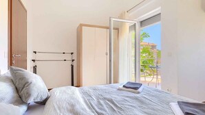 Une chambre à coucher comprenant un lit, une armoire et une porte-fenêtre coulissante donnant sur un espace extérieur.