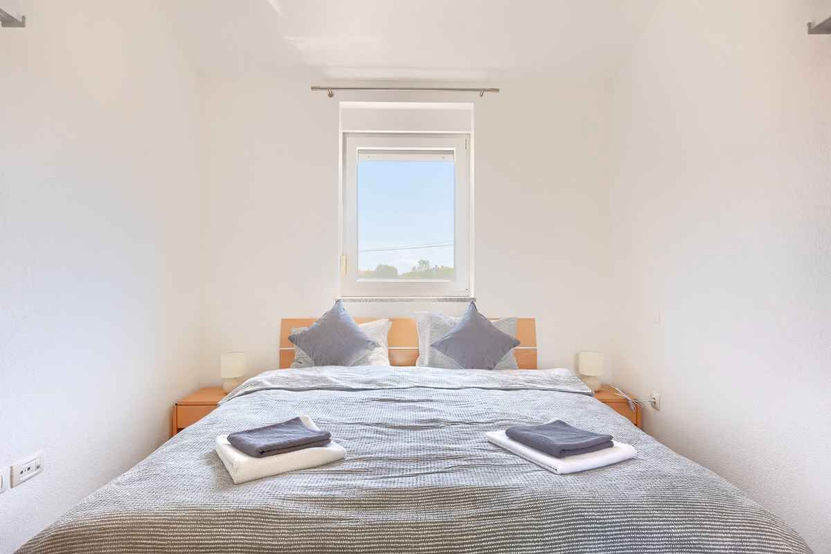Une chambre à coucher avec un lit, des oreillers, une table de chevet, une lampe et une fenêtre donnant sur un beau paysage.