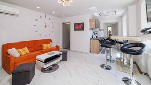 A modern living room with a sofa, a coffee table, and a kitchen area with bar stools. - Holiday apartment with large rooftop terrace and panoramic view (Bribir)