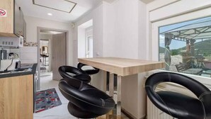 A modern kitchen with a wooden countertop, black leather bar stools, and a large window offering a view of the outdoors. - Holiday apartment with large rooftop terrace and panoramic view (Bribir)