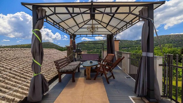 An outdoor patio with a table and chairs, a covered seating area, and a view of the surrounding landscape. - Holiday apartment with large rooftop terrace and panoramic view (Bribir)