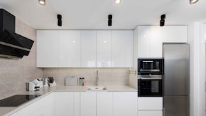 A modern kitchen with white cabinets, a stainless steel refrigerator, an oven, and a microwave. - Holiday home with outdoor pool, air conditioning and sea view (Punat)