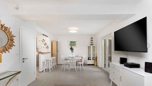 A modern, well-lit room with a dining area, a large flat-screen TV, and a minimalist design. - Holiday home with outdoor pool, air conditioning and sea view (Punat)