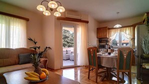 A living room with a sofa, coffee table with fruit, and a dining area with chairs and a table.