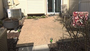 A residential backyard with a patio, a grill, and a covered outdoor seating area.
