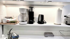 Eine moderne Küche mit Spüle aus Edelstahl, einer Kaffeemaschine, einem Toaster und einem Wasserkocher.