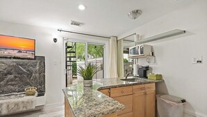 Uma cozinha moderna com bancadas de granito, armários de madeira e micro-ondas embutido.