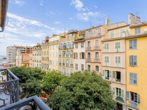 A row of colorful buildings with balconies, a clear sky, and lush greenery in the foreground. - Lafayette by Interhome (Toulon)