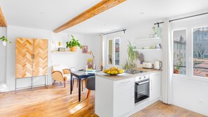 A modern kitchen with wooden beams, a dining area, and a view of the city. - T2 Bazeilles by Interhome (Toulon)