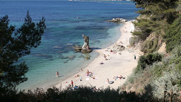 A beach with clear water, a rocky outcrop, and people sunbathing. - T2 Bazeilles by Interhome (Toulon)