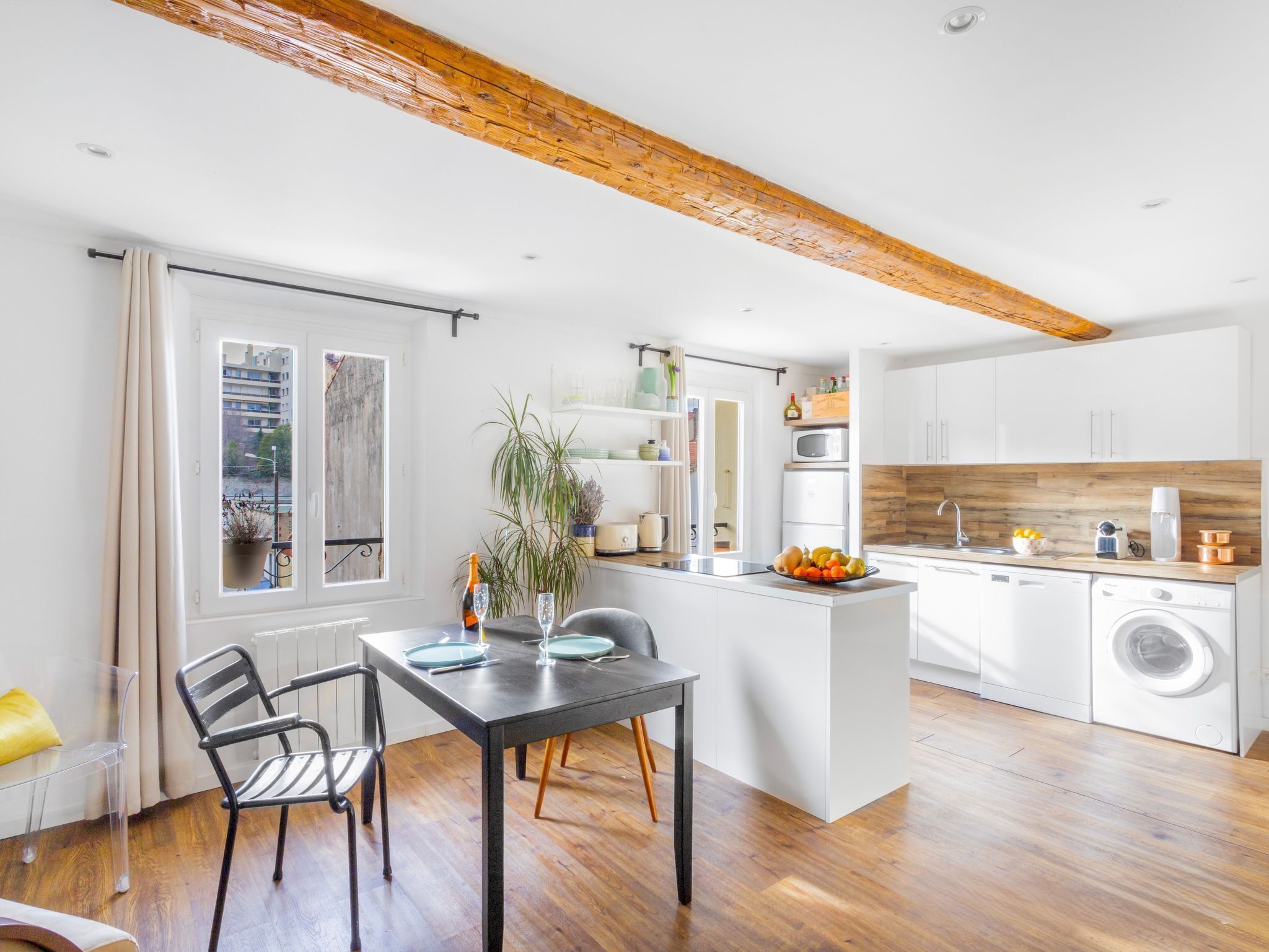 Eine moderne Küche mit weißen Schränken, einer Holzbalkendecke und einem Essbereich mit Tisch und Stühlen.