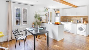 A modern kitchen with white cabinets, a wooden ceiling, and a dining area with a table and chairs. - T2 Bazeilles by Interhome (Toulon)