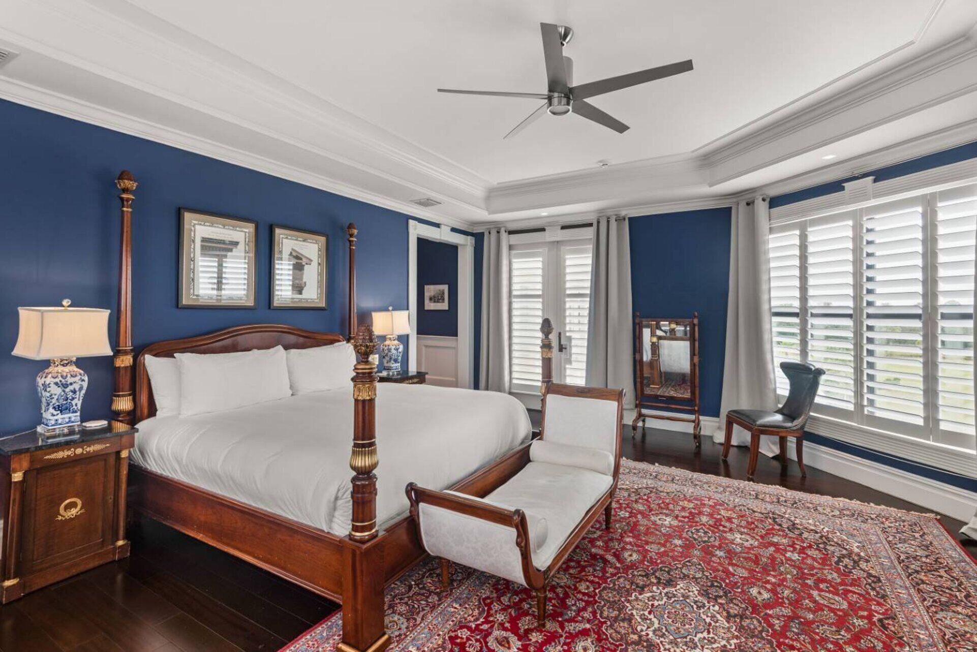 Une chambre à coucher avec un lit à baldaquin, un grand tapis rouge à motifs et un ventilateur de plafond.
