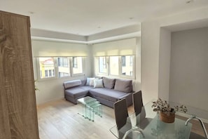 Una sala de estar moderna con un sofá modular, una mesa de centro de vidrio y un comedor con mesa y sillas de vidrio.
