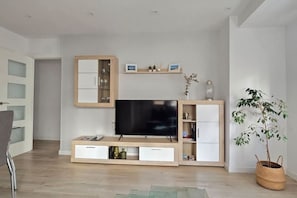Una sala moderna con un televisor de pantalla plana, estanterías empotradas y una planta en maceta.