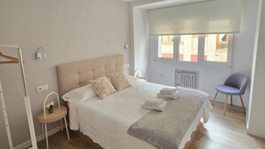 Una camera da letto con un letto grande, comodini, una sedia e una finestra con persiane.