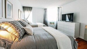 Ein modernes Schlafzimmer mit einem großen Bett, einem Fernseher und einer Kommode.