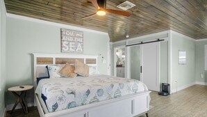 Ein Schlafzimmer mit Bett, Deckenventilator, einer Wandtafel und einer Tür.
