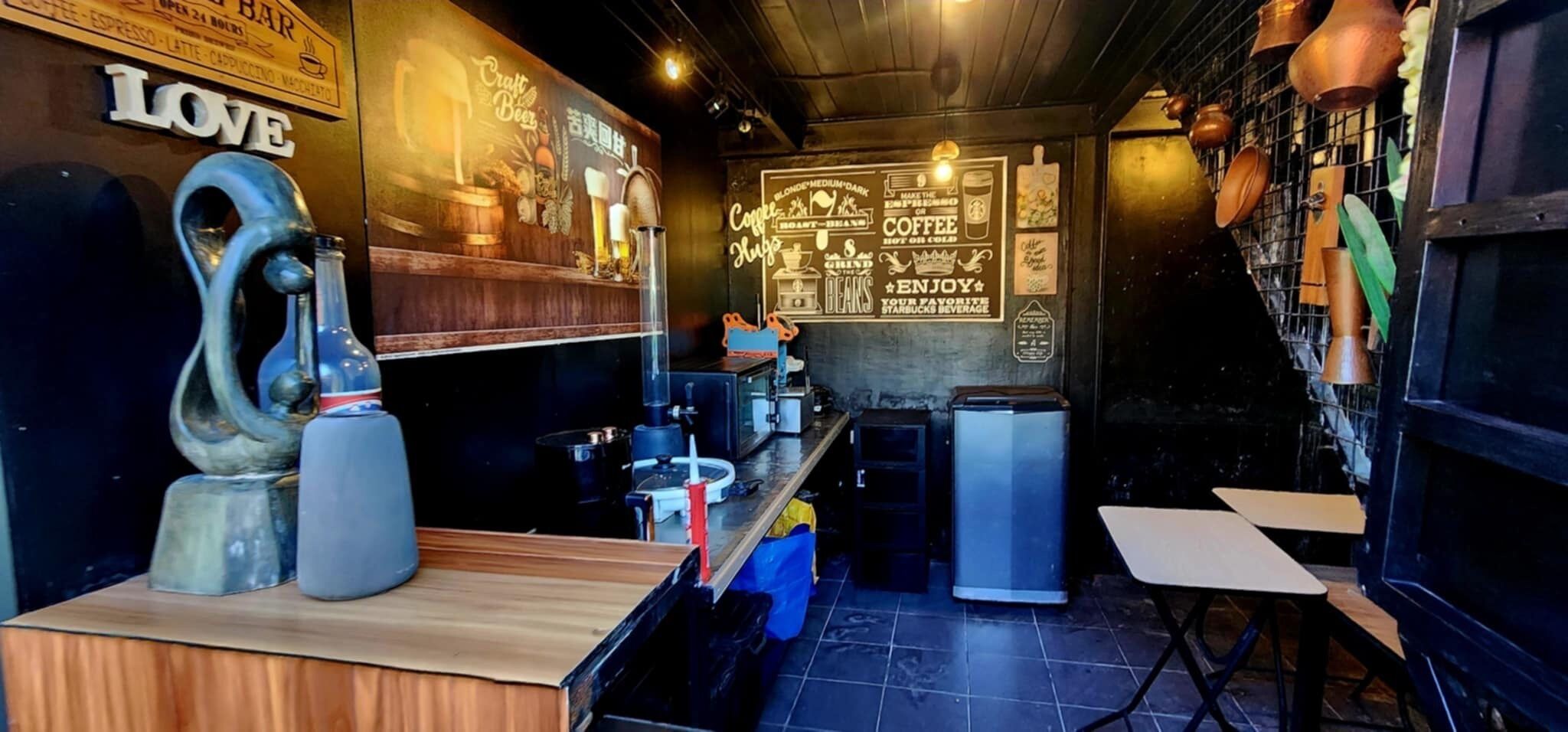 Un bar acogedor con mostrador de madera, una escultura decorativa y una pizarra con frases sobre café.