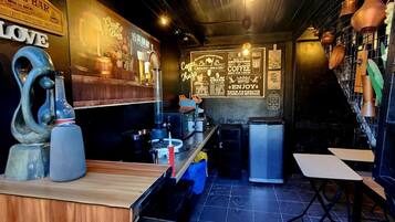 Un bar acogedor con mostrador de madera, una escultura decorativa y una pizarra con frases sobre café.