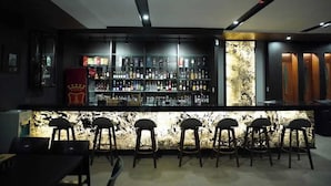 A bar area with a counter, stools, and a variety of bottles. - Rocca Del Garda Resort (Cardona)