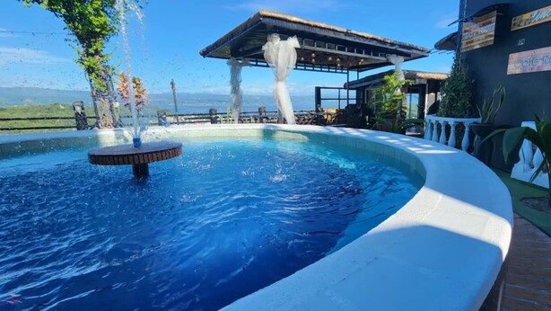 A swimming pool with a water fountain, a covered seating area, and a sign that reads "Cafe Roca". - Rocca Del Garda Resort (Cardona)