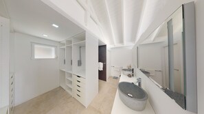 A modern bathroom with a large mirror, a round sink, and a built-in storage unit.