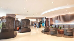 A modern lobby with seating areas, a reception desk, and a curved wall with vertical lines. - Shawnalyn condotel at Mall of Asia,Philippines (Pasay)
