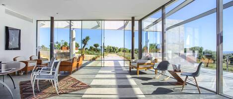 A spacious room with large windows, a dining area, and a view of the outdoors.