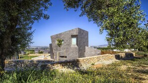 A modern building with a stone facade, surrounded by greenery and a clear sky. - Retiro 4 Empis (4 guests) (Arcos De La Frontera)