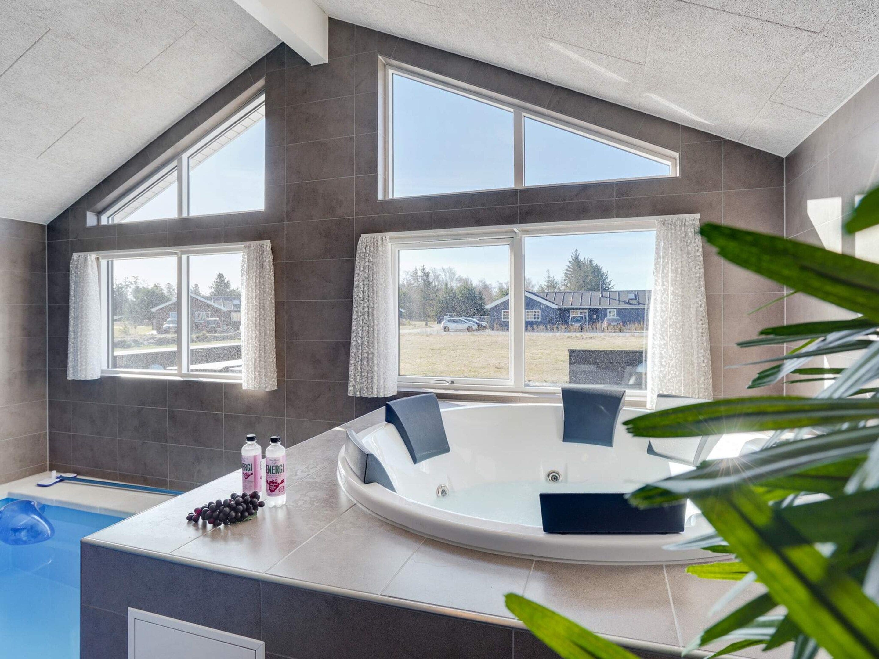 Ein modernes Badezimmer mit einer Badewanne, großen Fenstern und Blick ins Freie.