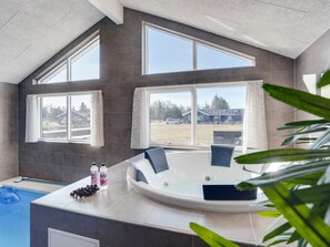 Un baño moderno con bañera, ventanas amplias y vistas al exterior.