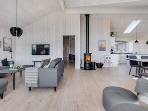 Una sala de estar moderna con chimenea, comedor y cocina.