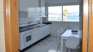 A compact kitchen with white cabinets, a black countertop, and a window overlooking a body of water. - Cozy apartment with views in Sada (Sada)