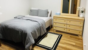 Une chambre à coucher avec un lit, une commode, un miroir et un tableau encadré accroché au mur.