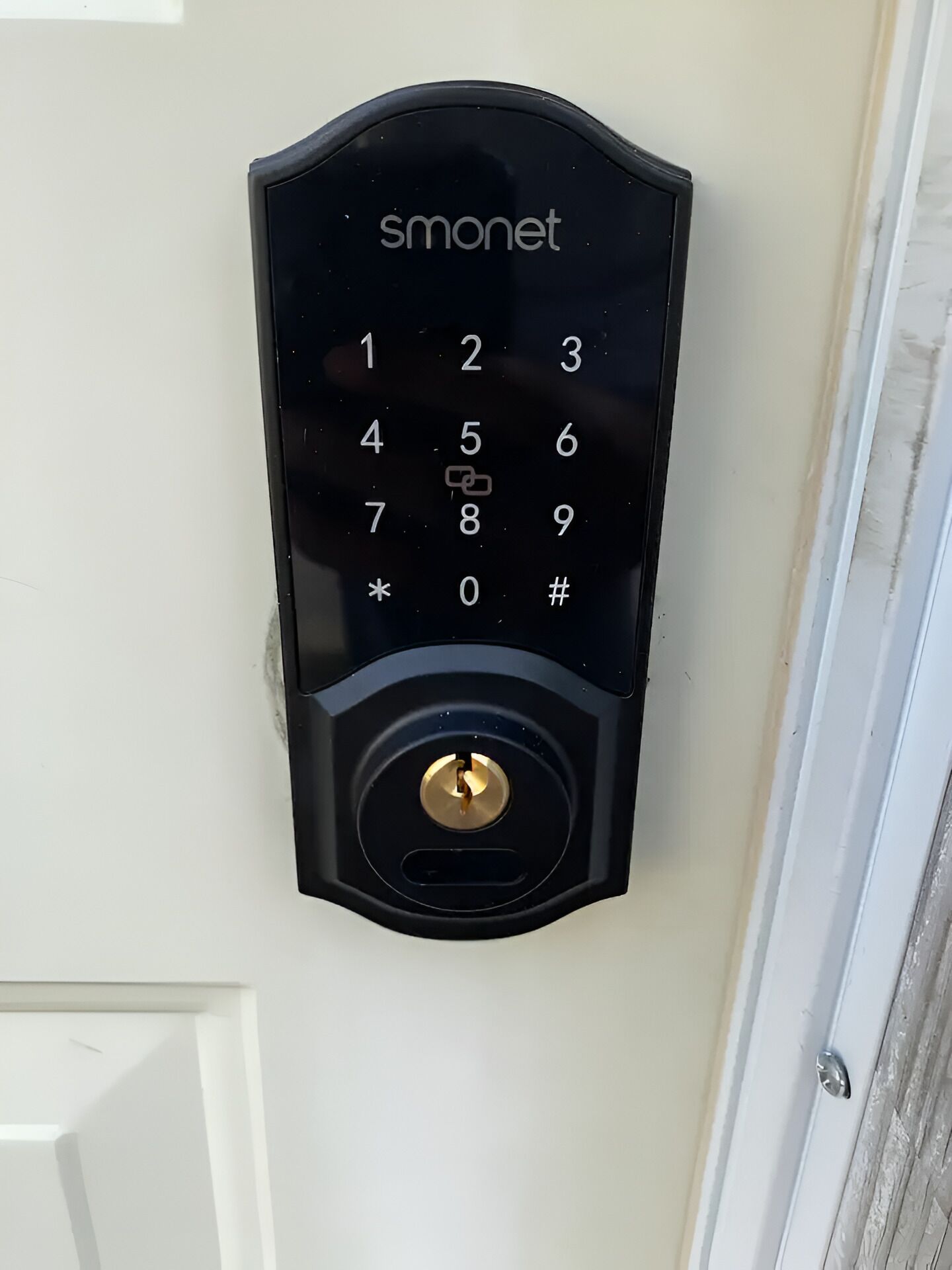 Een zwart Smonet keypad slot op een witte deur.
