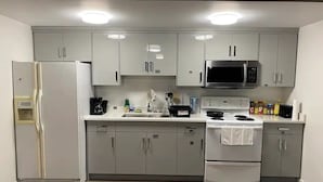 Une cuisine moderne avec des meubles gris, un réfrigérateur blanc, un four à micro-ondes, une cuisinière et un lave-vaisselle.