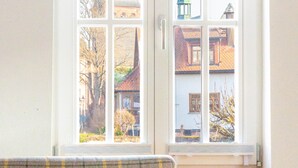 Une pièce avec un canapé et une fenêtre donnant sur un bâtiment surmonté d’une flèche verte.