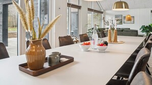 Un comedor moderno con una mesa larga, sillas y lámparas colgantes.
